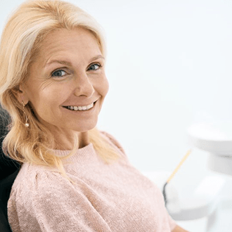 a woman smiling after receiving her dental implants