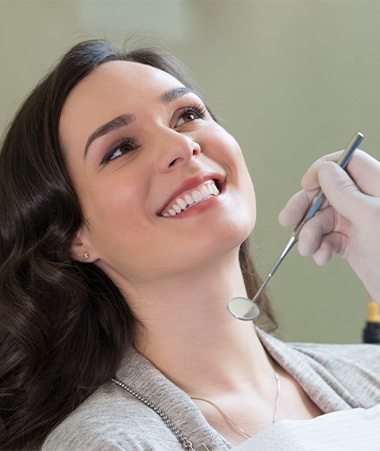 Smiling woman in dental chair after one visit dental restoration