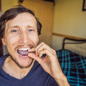 Man sitting on bed putting in his nightguard