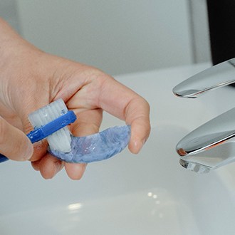 Brushing a nightguard with a double-headed toothbrush