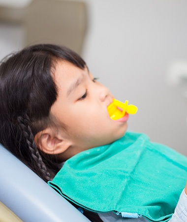 Child relaxing in dental chair during fluoride treatment