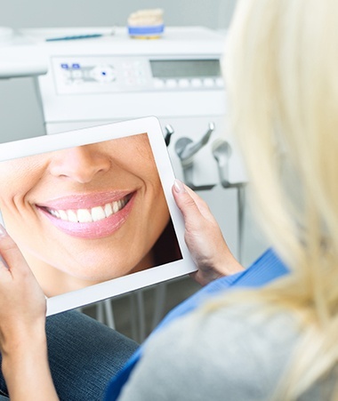 Woman looking at her smile design on tablet computer