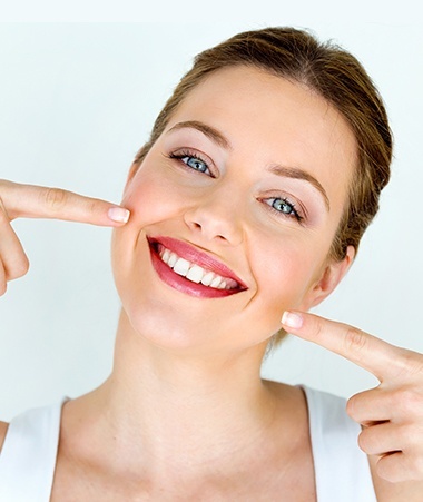 Woman pointing to beautiful smile after makeover