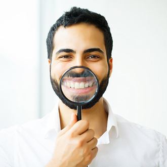 man holding a magnifying glass to his smile 