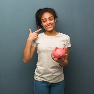 woman holding piggy bank and pointing to her smile 