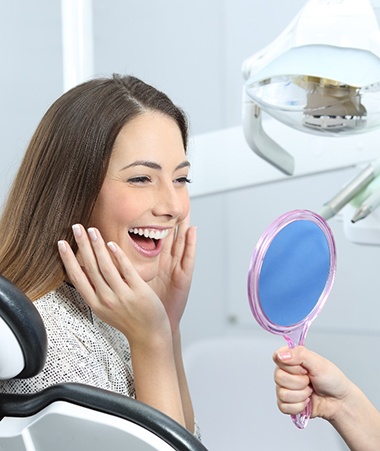 Smiling woman admiring her new dental crowns in Springfield