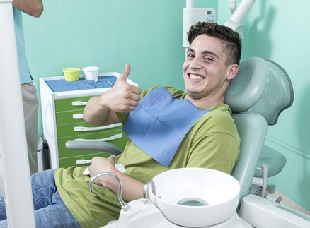 Man smiling giving thumbs up after dental checkup and teeth cleaning
