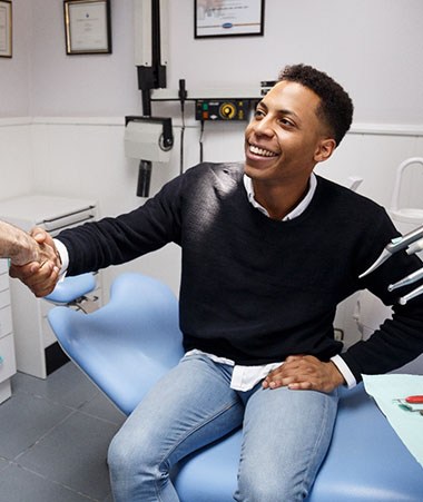 A male patient shaking hands with his dentist during a regular visit