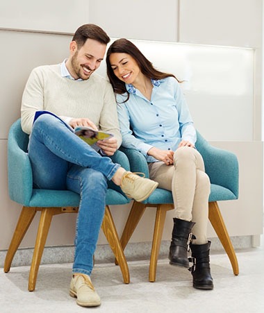 A young couple seated in the lobby learning about dental services