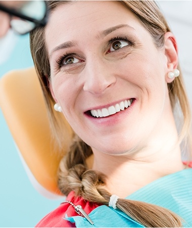Smiling woman in dental chair for dental implant tooth replacement