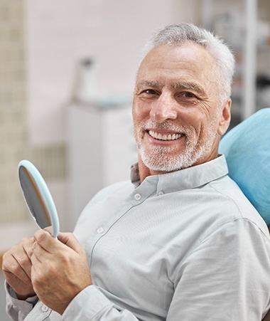 senior man smiling after getting dentures in Springfield 