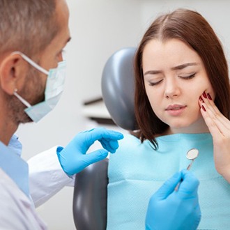 young woman in pain while talking to her dentist