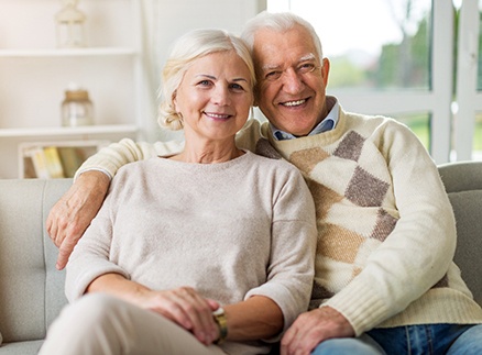 An older couple smiling after receiving their implant dentures in Springfield