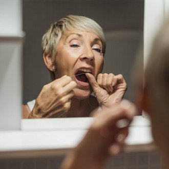 : a woman flossing her dental implants