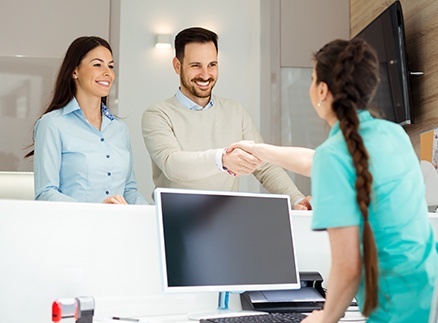 Man and woman checking in at dental reception desk