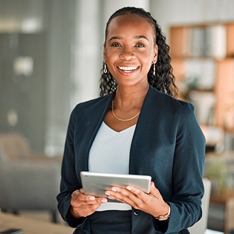 Woman smiling while holding tablet in office