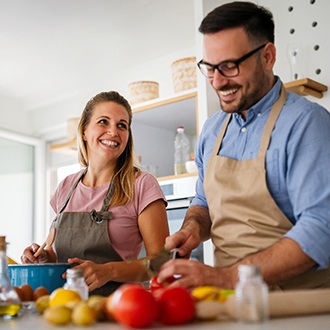 Couple smiling while preparing meal in kitchen