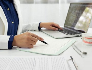 a dentist filling out forms while looking at an X-ray