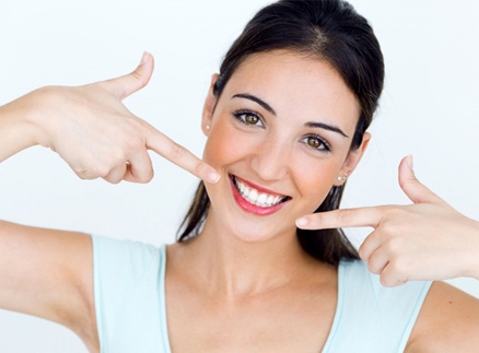 young woman pointing to her smile straightened by Invisalign in Springfield