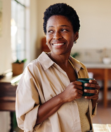 Woman smiling while drinking coffee at home