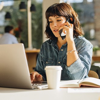 Woman talking on phone while working on laptop