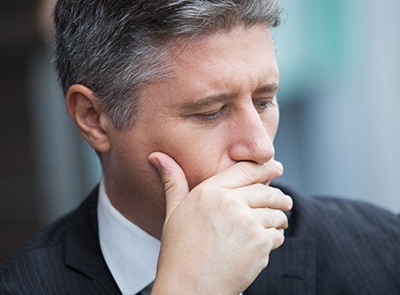 Man who needs to replace missing teeth covering his mouth