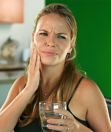 Woman in pain holding cheek before replacing missing teeth