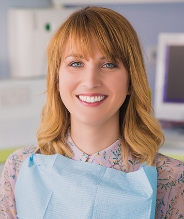 Woman in dental chair smiling after dental checkup and teeth cleaning