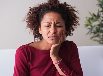 Woman in need of root canal therapy holding jaw