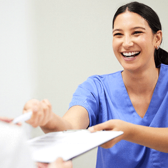 dental assistant smiling while handing patient form