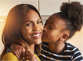 Daughter giving mother a kiss on the cheek after preventive dentistry visit