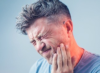 Man in need of emergency dentistry holding jaw