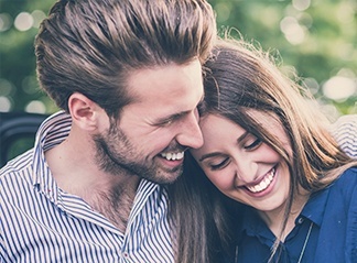 Young man and woman smiling outdoors after cosmetic dentistry