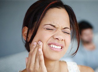 Woman in need of emergency dentistry holding jaw