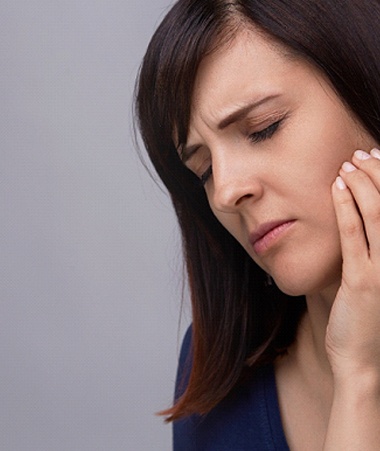 Woman with dental pain touching her cheek