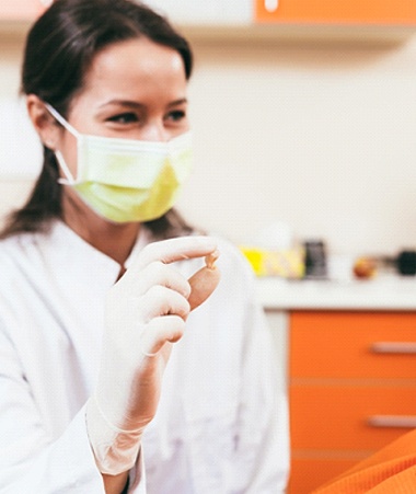 Dentist showing smiling patient her extracted tooth