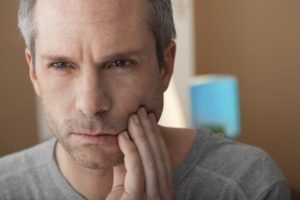 man holding his jaw in pain