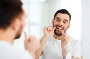 man flossing in front of a mirror 