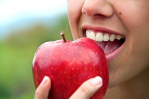 person eating a red apple after teeth whitening in Springfield 