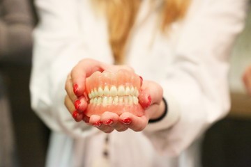 emergency dentist holding out tooth model