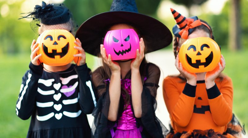 Kids hiding their heads behind pumpkin buckets