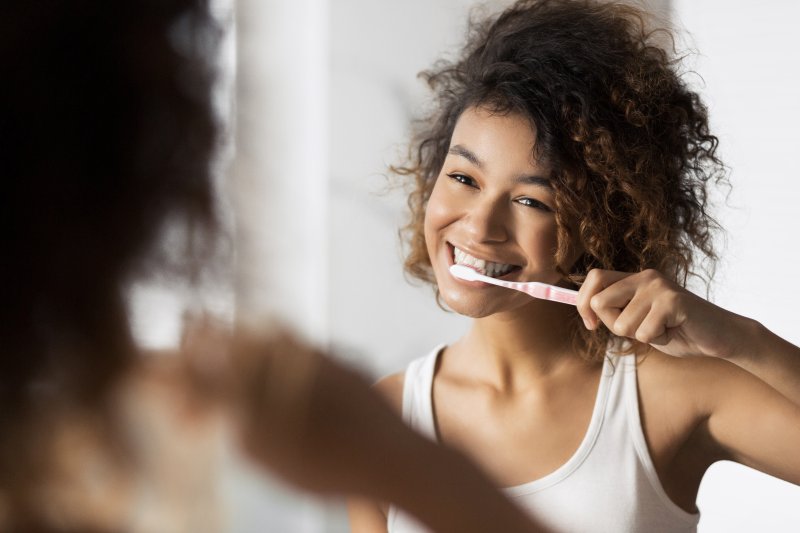 Woman smiling as she brushes her new dental implants