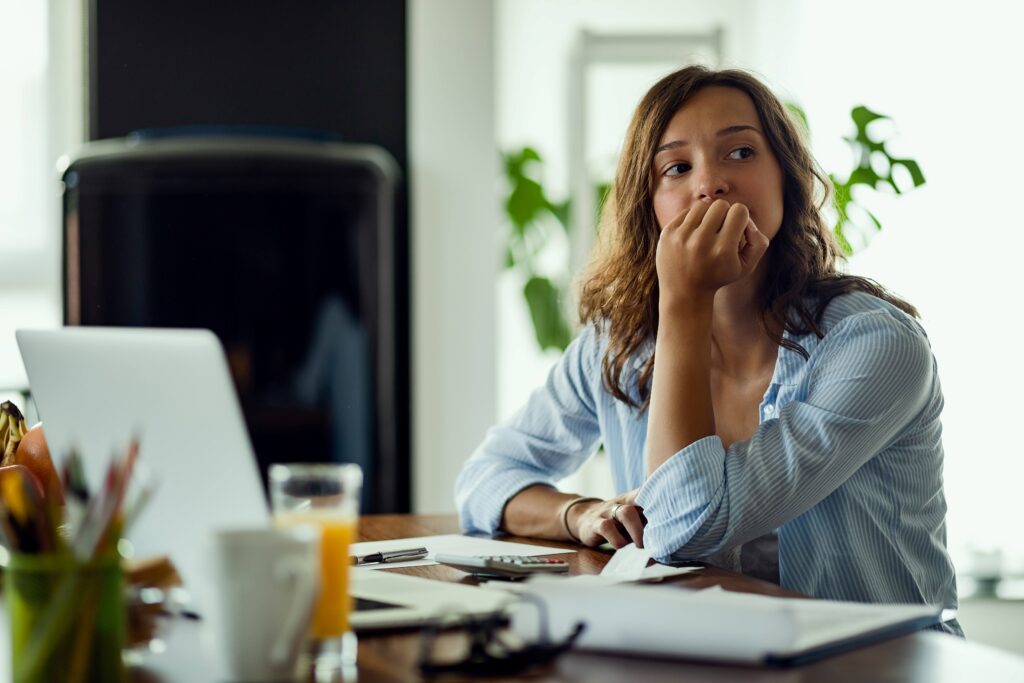 Woman looking worried while sitting at desk at home