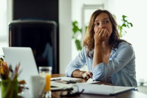 Woman looking worried while sitting at desk at home