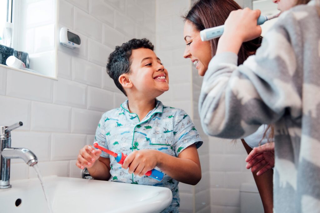 Woman and little boy brushing teeth with electric brushes