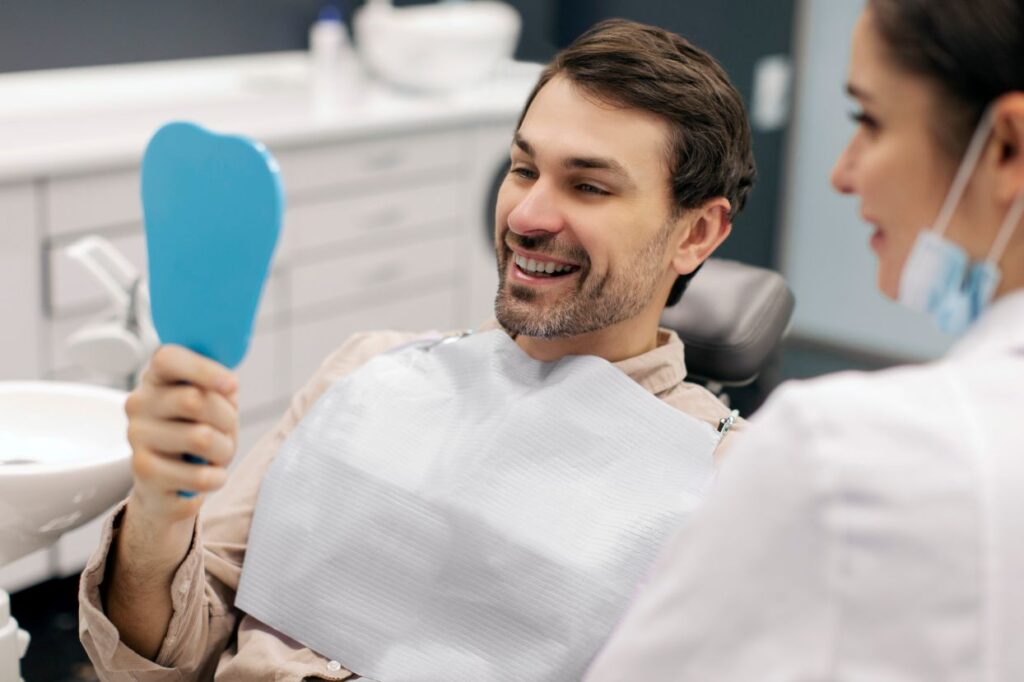 A man looking in a mirror after his smile makeover